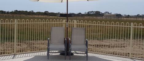 A poolside area with two chairs and a white umbrella.