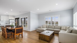 A spacious living area with a wooden dining table, a beige sofa, and a coffee table.