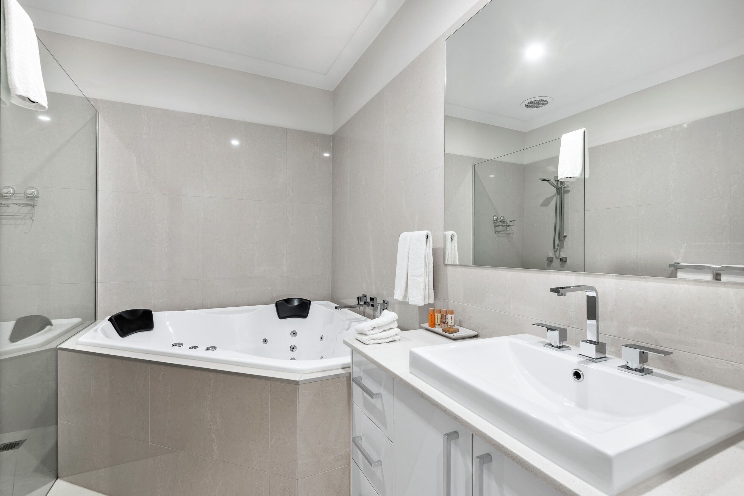A modern bathroom with a large bathtub, a separate shower area, and a vanity with a sink.