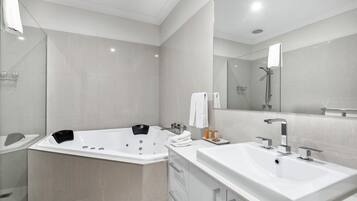 A modern bathroom with a large bathtub, a separate shower area, and a vanity with a sink.