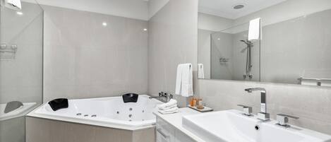 A modern bathroom with a large bathtub, a separate shower area, and a vanity with a sink.