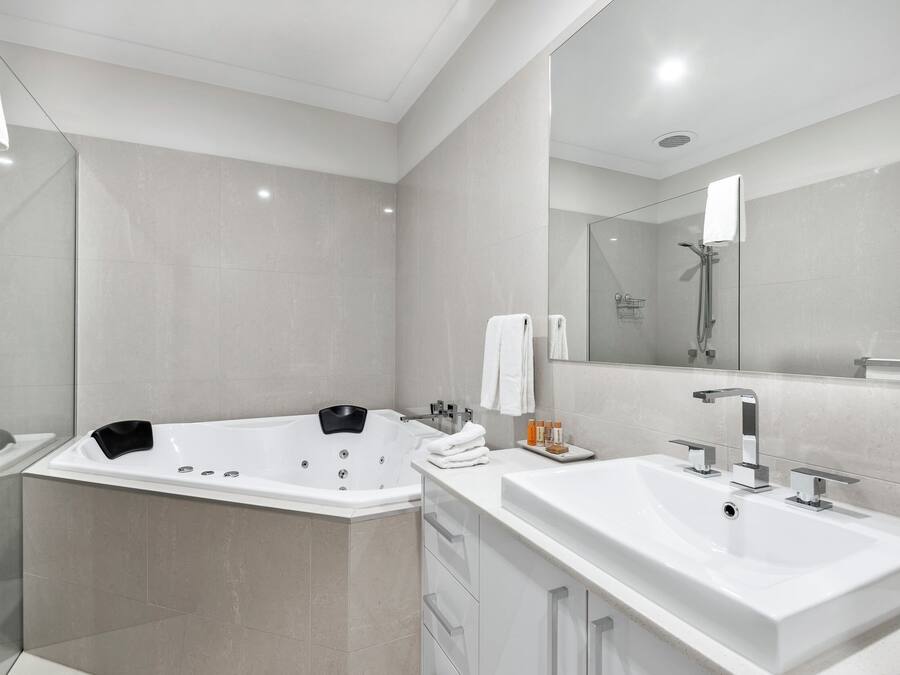 A modern bathroom with a large bathtub, a separate shower area, and a vanity with a sink.