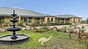 A building with a fountain, a bicycle, and a bird sculpture in the garden.