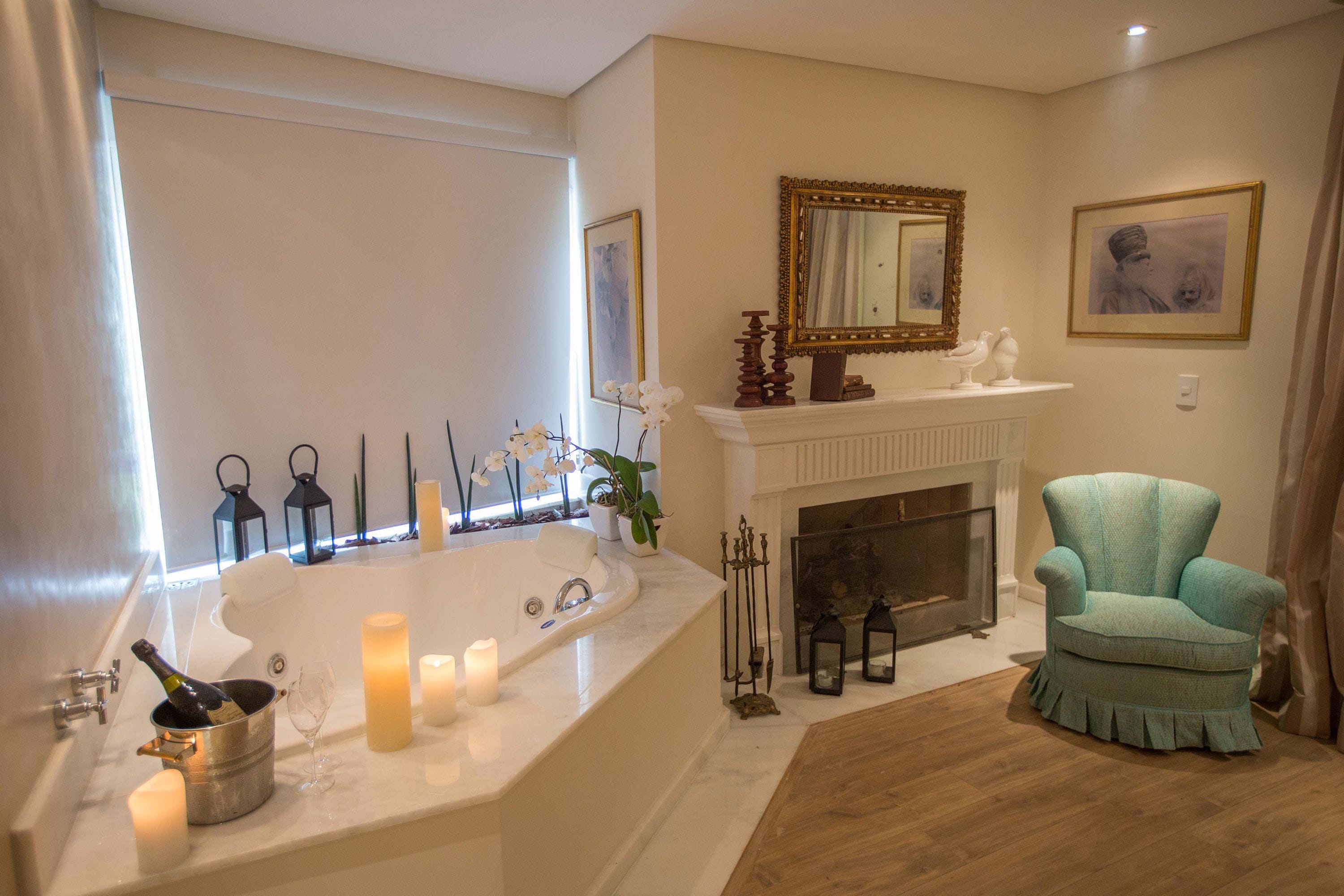 Un baño con una bañera grande, una chimenea y un sillón color turquesa.