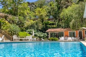 Una piscina al aire libre, sombrillas, sillones reclinables de piscina