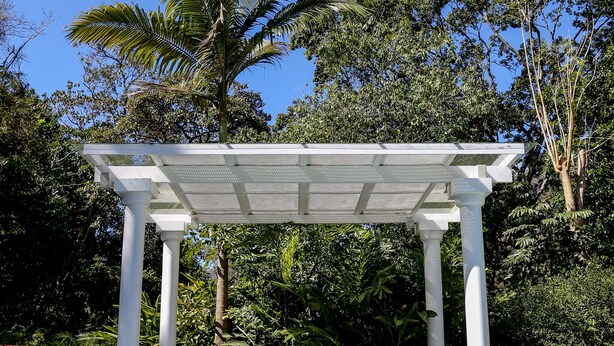 A pool area with a pergola, white chairs, and lush greenery in the background. - Locanda Della Mimosa (Petrópolis)