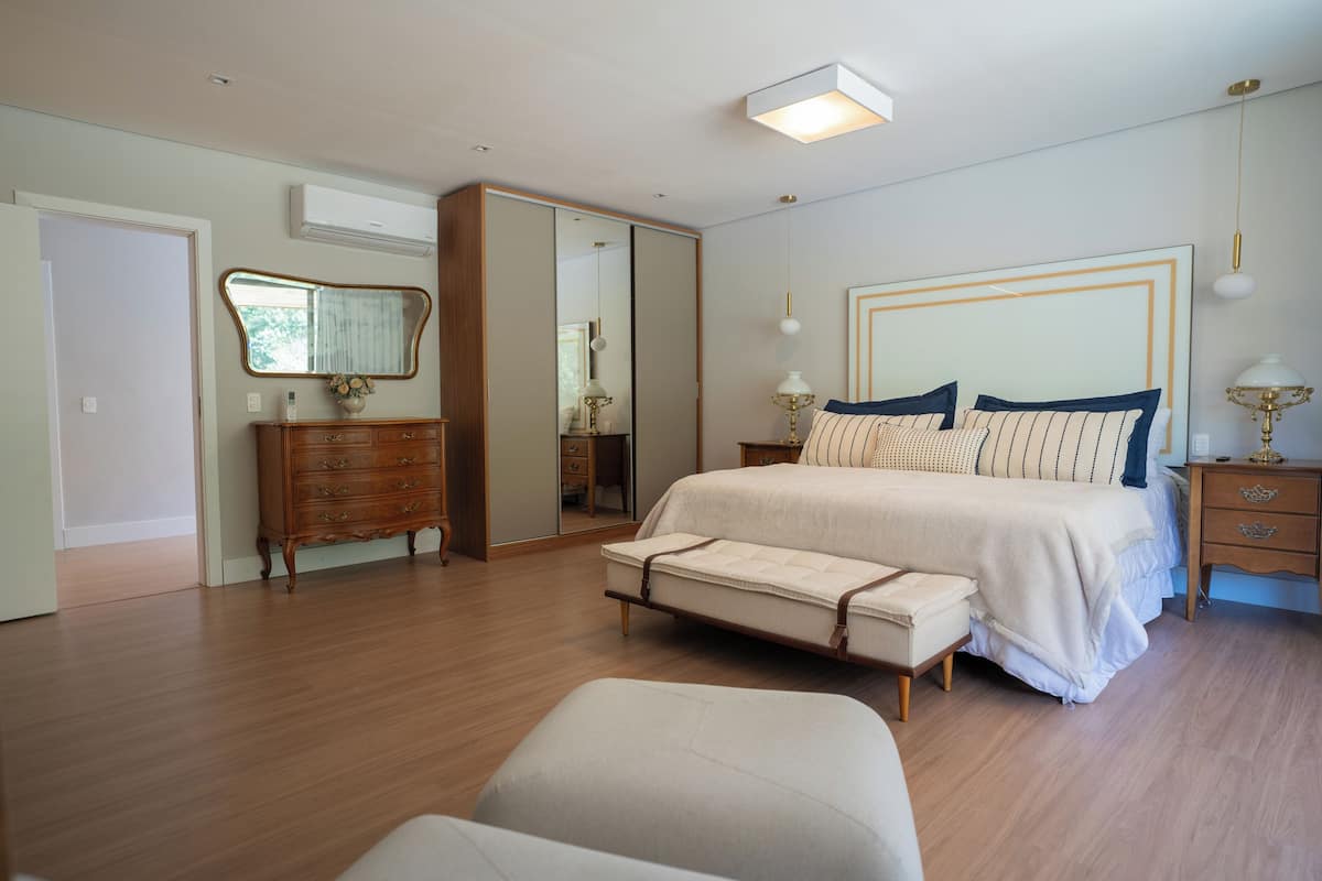 A bedroom with a bed, bedside tables, a dresser, a mirror, and a ceiling light fixture.