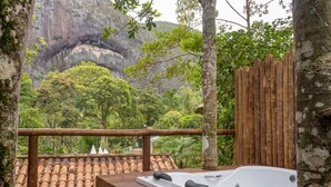 A wooden deck with a hot tub overlooking a lush forest and a cliff. - Locanda Della Mimosa (Petrópolis)