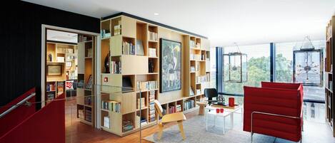 A modern library with bookshelves, a red chair, and a glass partition.
