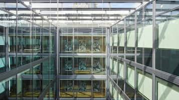 A modern glass-walled atrium with multiple levels and a central staircase.