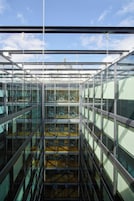 A modern glass-walled atrium with multiple levels and a central staircase.