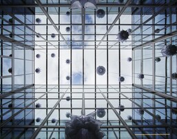 A modern glass ceiling with geometric patterns and hanging spherical decorations.