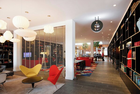 A modern library with bookshelves, a red sofa, and a yellow chair.