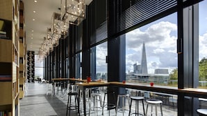 A modern library with bookshelves, reading tables, and bar stools. - citizenM Tower of London (London)