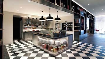 A modern kitchen with a central island, black pendant lights, and a checkered floor.