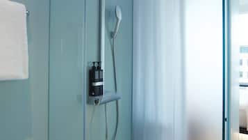 A modern bathroom with a glass shower enclosure, a handheld showerhead, and a control panel.