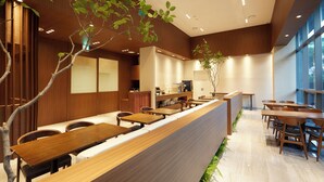Ein modernes Restaurant mit Holztischen und -stühlen, einer Theke und großen Fenstern.