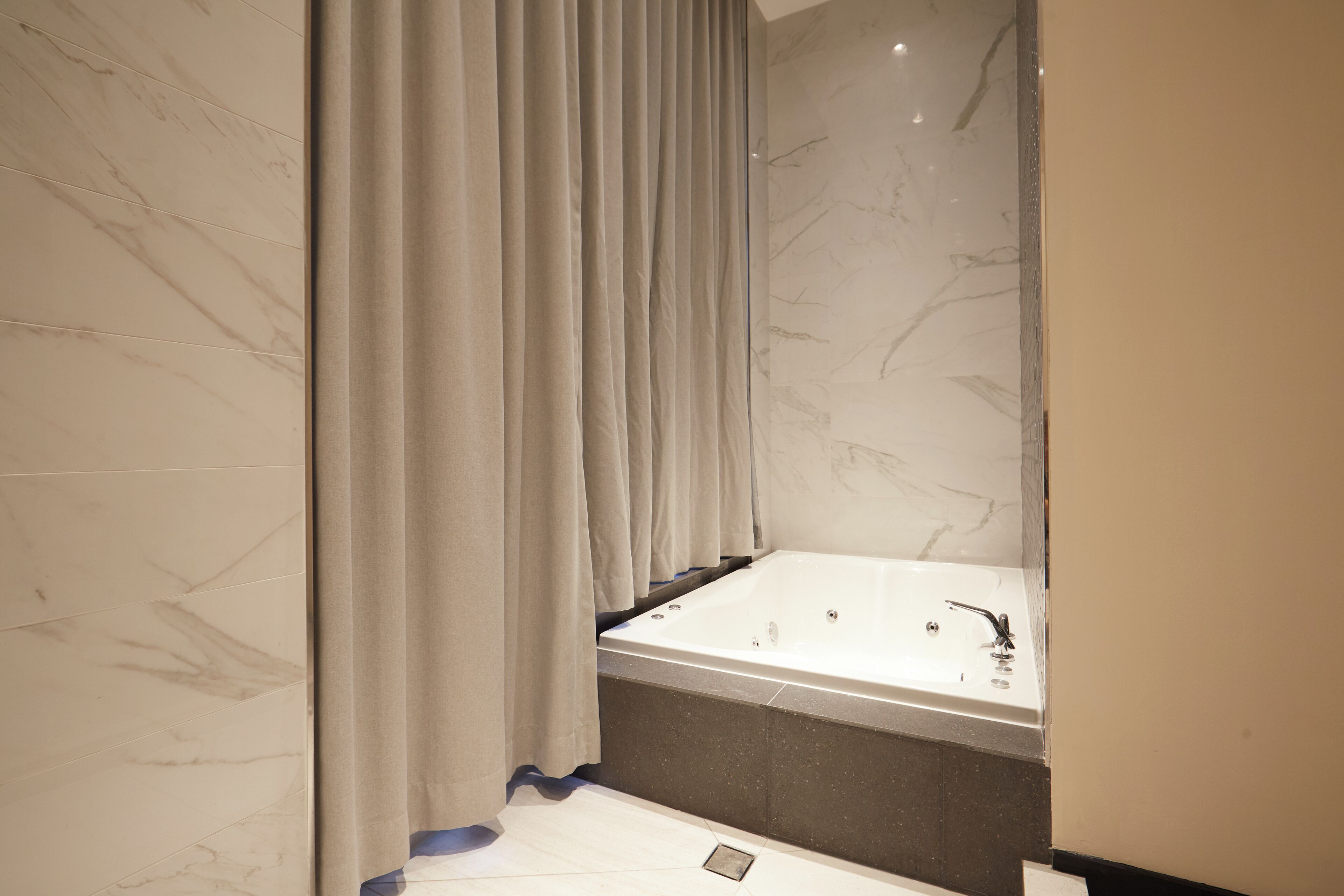 A modern bathroom with a marble wall, a bathtub, and a shower curtain.