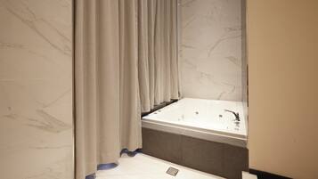 A modern bathroom with a marble wall, a bathtub, and a shower curtain.