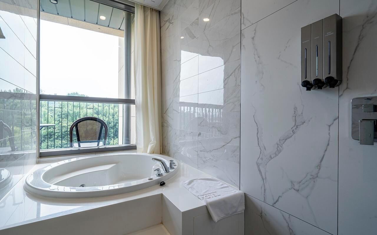 Un baño moderno con una bañera grande, una ventana con vistas y un perchero para toallas.