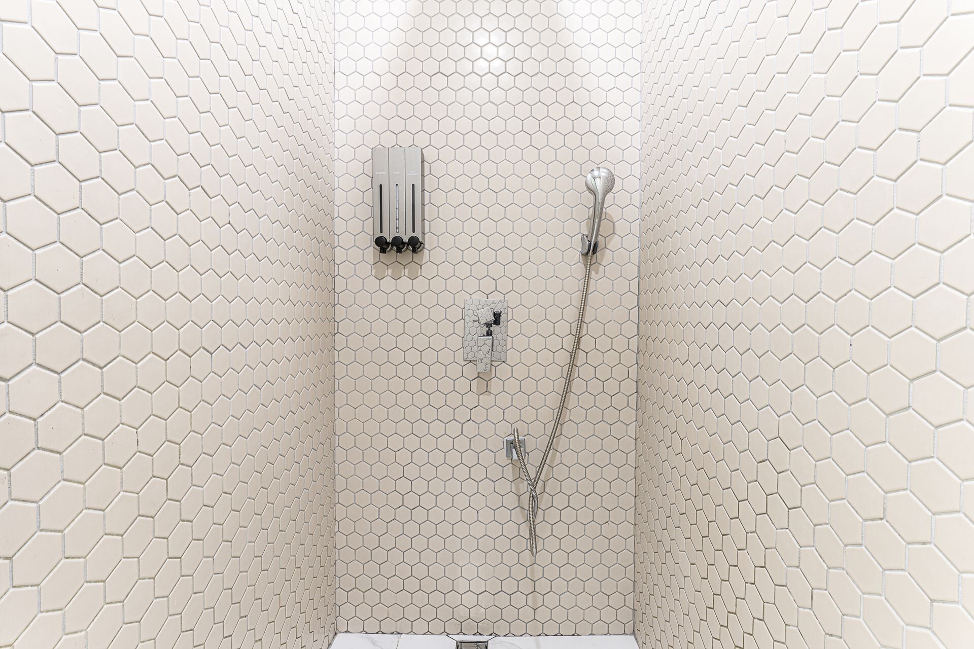 A shower with a hexagonal tile pattern on the walls and a glass-enclosed shower area.