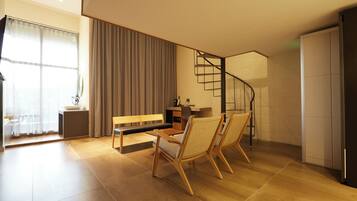 A modern living room with a sofa, two chairs, a coffee table, and a staircase leading to an upper level.