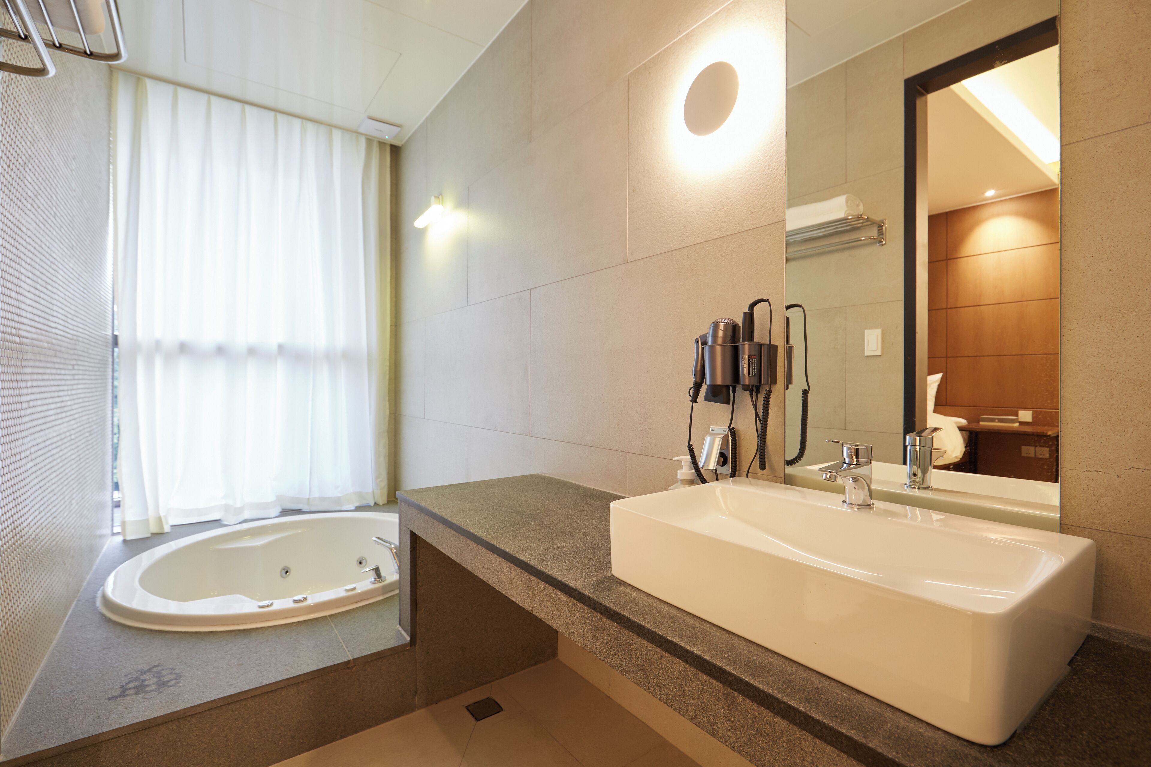 A modern bathroom with a large bathtub, a separate sink, and a mirror.