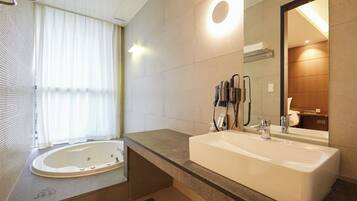 A modern bathroom with a large bathtub, a separate sink, and a mirror.