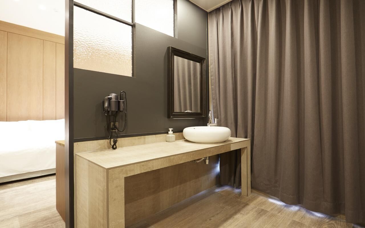A modern bathroom with a wooden vanity, a mirror, a sink, and a shower area.