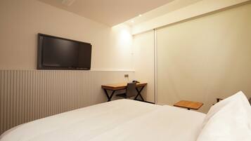 Una habitación de hotel con cama, escritorio, silla, televisor y una mesita.
