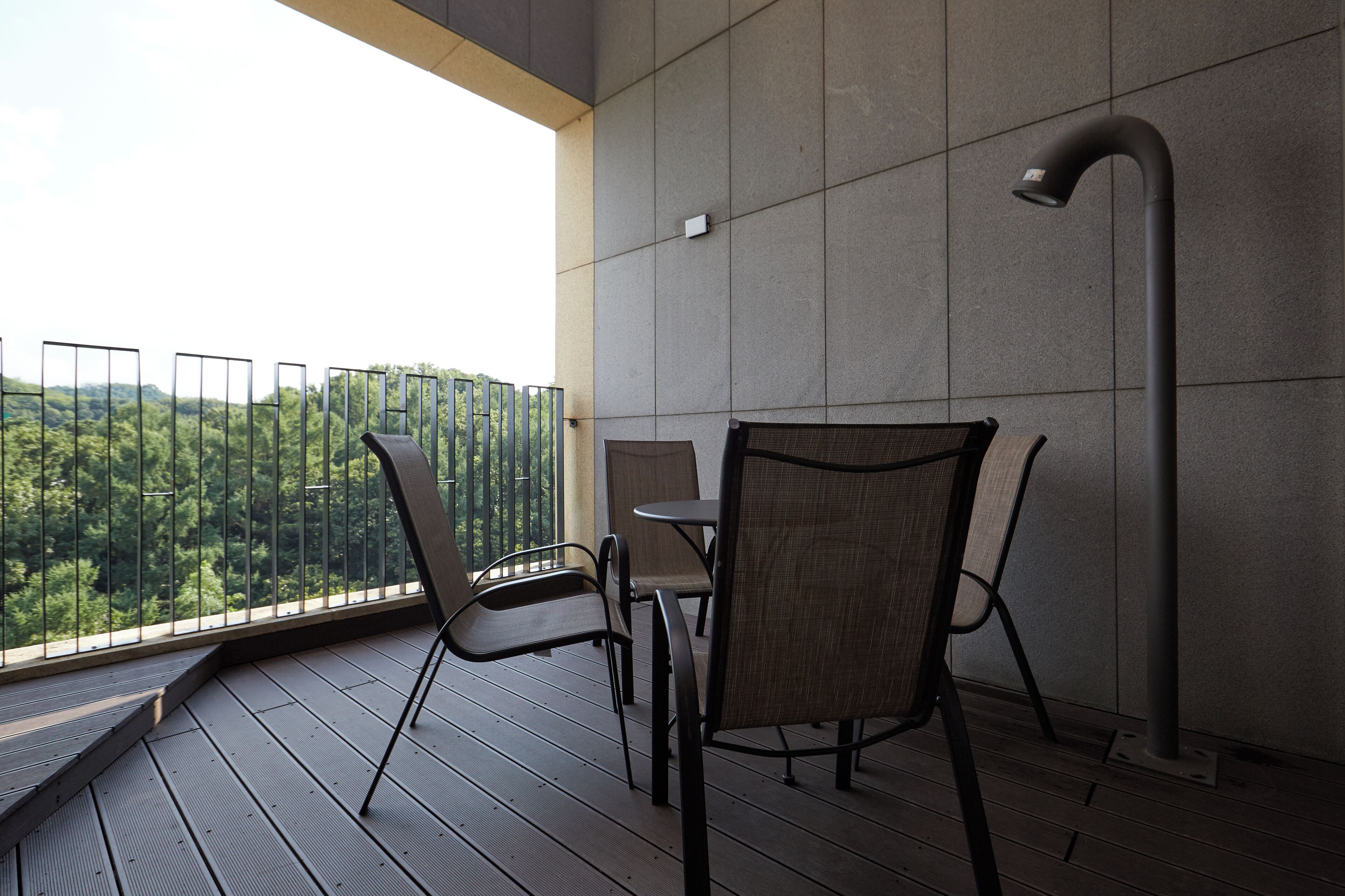 A balcony with a view of a forest, a table, and two chairs.