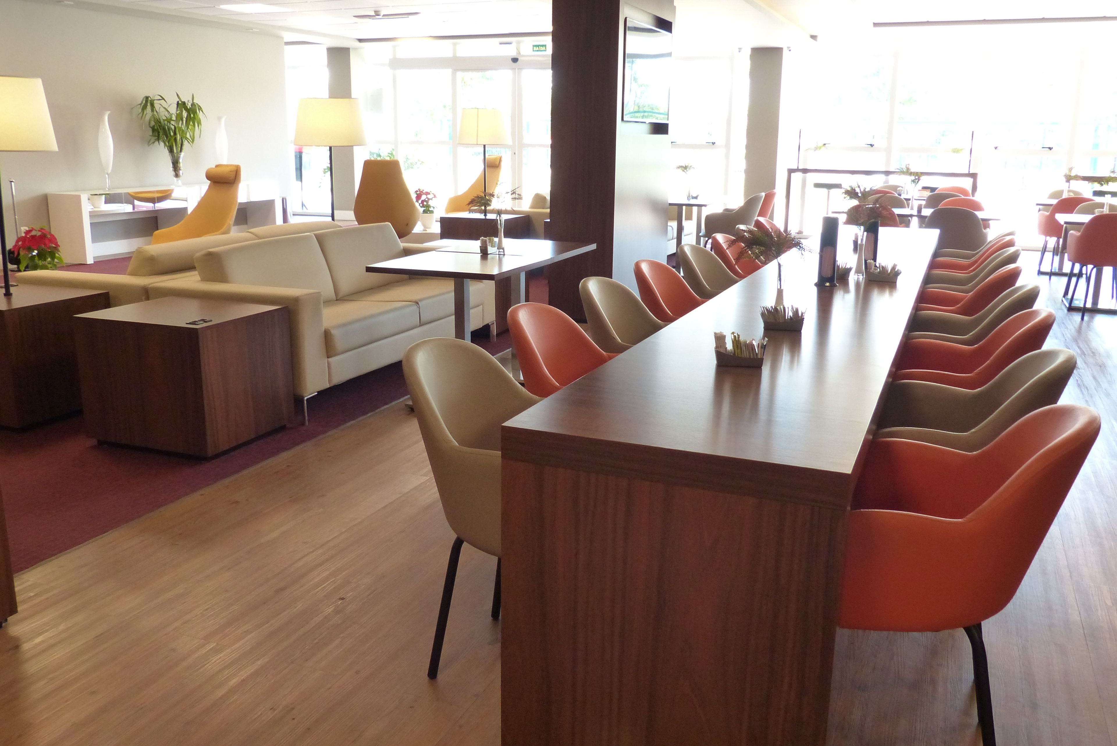 Un moderno vestíbulo de hotel con un largo mostrador de recepción de madera, asientos cómodos y ventanas amplias.