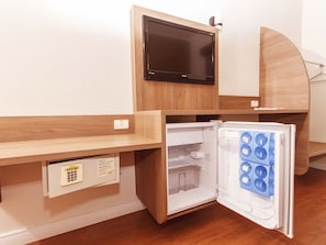 Uma cozinha compacta equipada com micro-ondas, mini-geladeira com compartimento para congelamento e painel de controle com botão de energia e pequena tela.