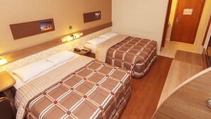 A hotel room with two beds, a desk, a chair, a nightstand, and a door. - Hotel 10 Palmas (Palmas)