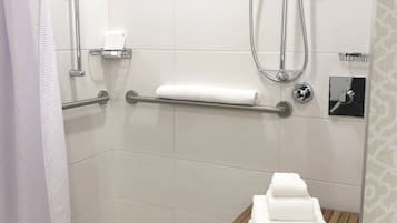 A shower area with a grab bar, a towel rack, and a wooden shelf with towels.