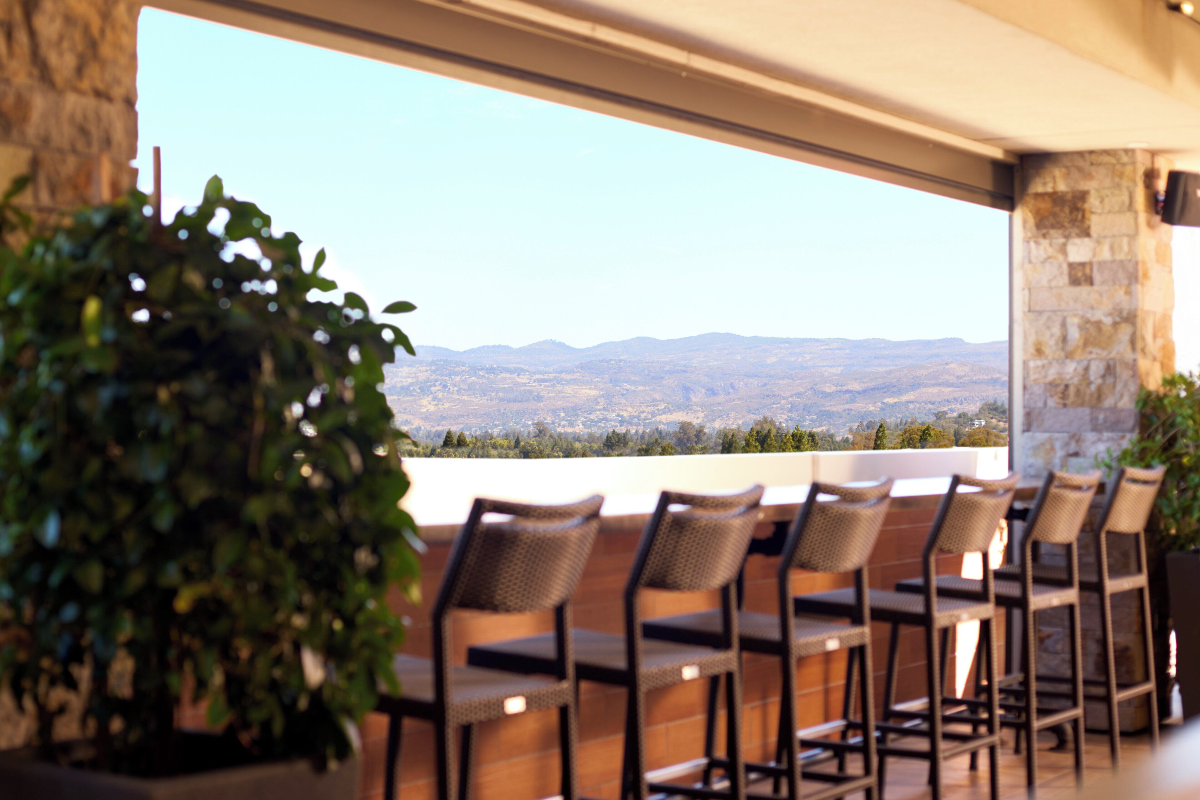 Une terrasse dotée de chaises et d’une table en osier, offrant une vue sur un paysage montagneux.