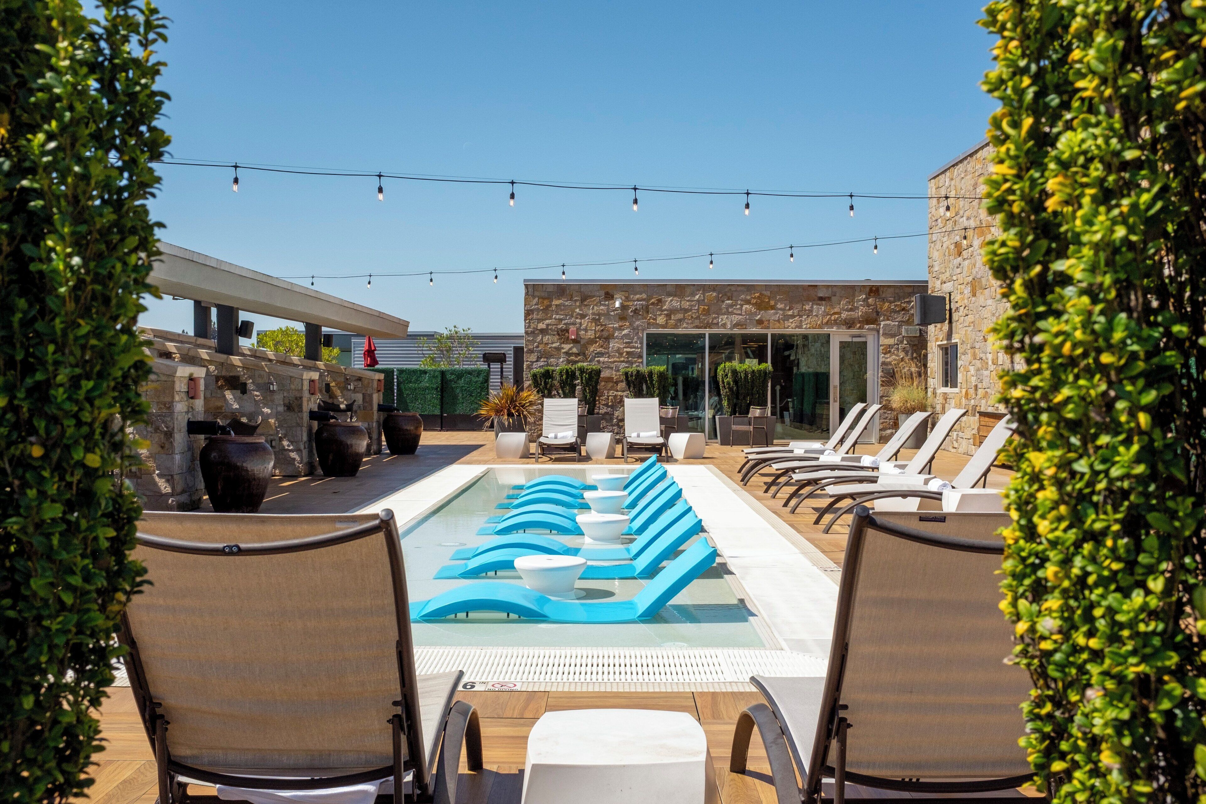 A pool area with lounge chairs and a stone building in the background.