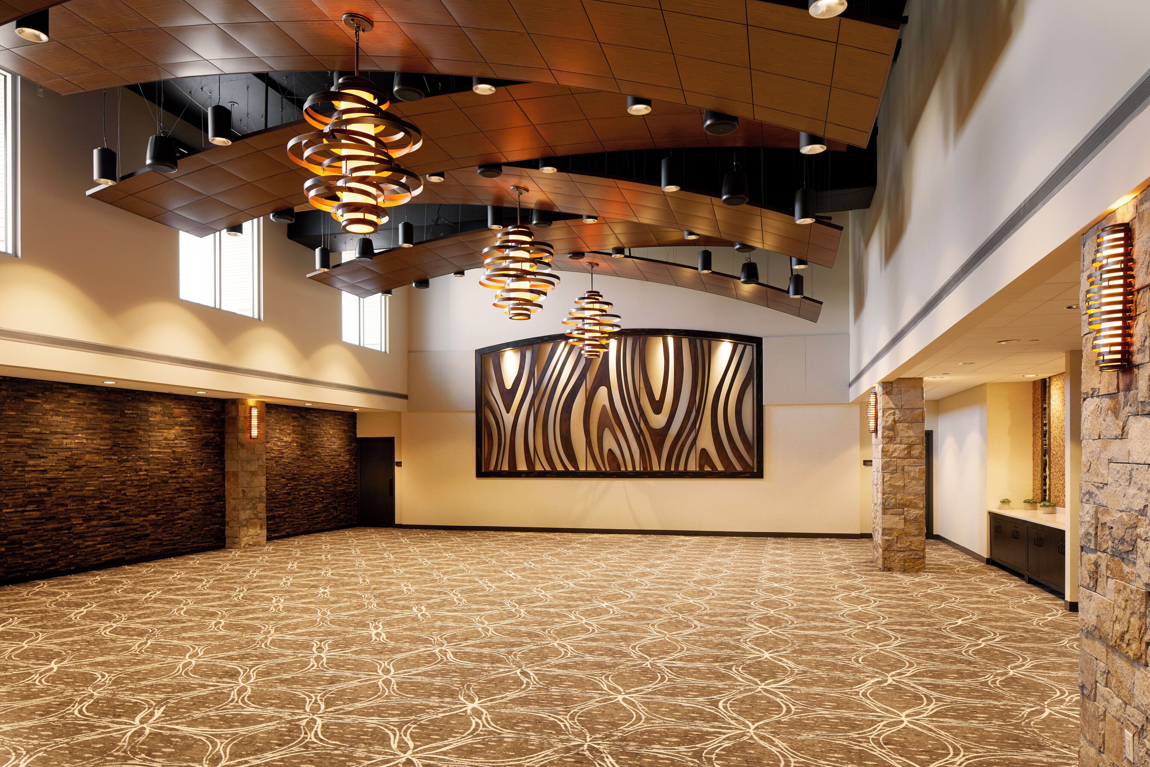 A spacious hall with patterned carpet, modern lighting fixtures, and a large abstract wall art piece.