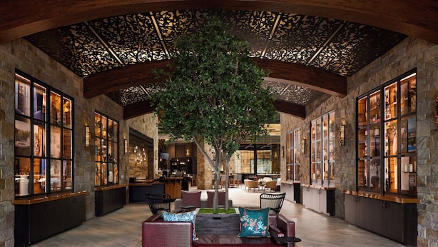A spacious lobby with a central seating area, stone walls, and a large tree. - Archer Hotel Napa (Napa)