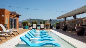 A rooftop pool with lounge chairs, a view of mountains, and string lights. - Archer Hotel Napa (Napa)
