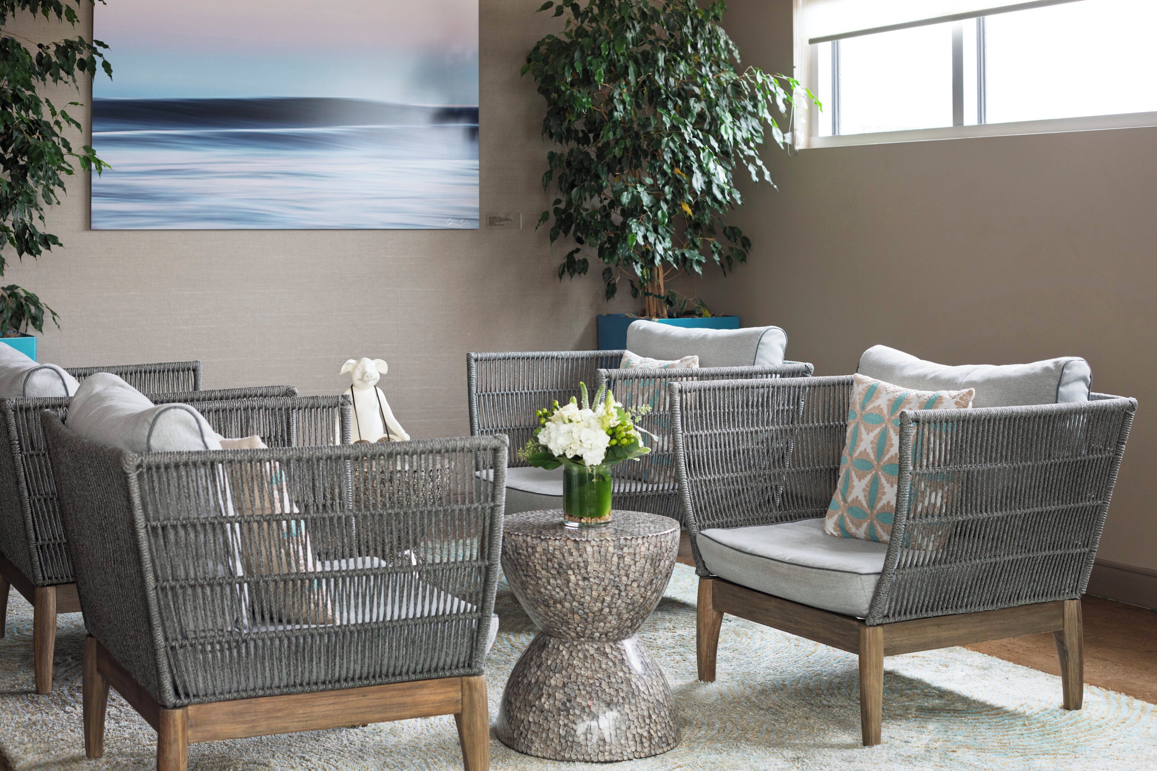 A room with wicker furniture, a stone coffee table, and a large plant.