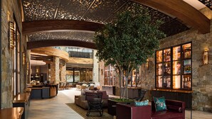 A spacious lobby with a high ceiling, stone walls, and a central seating area with a red sofa and chairs. - Archer Hotel Napa (Napa)