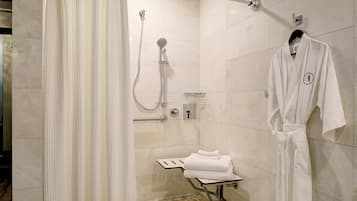 Un baño moderno con cabina de ducha de vidrio, perchero y asiento de ducha de cristal.