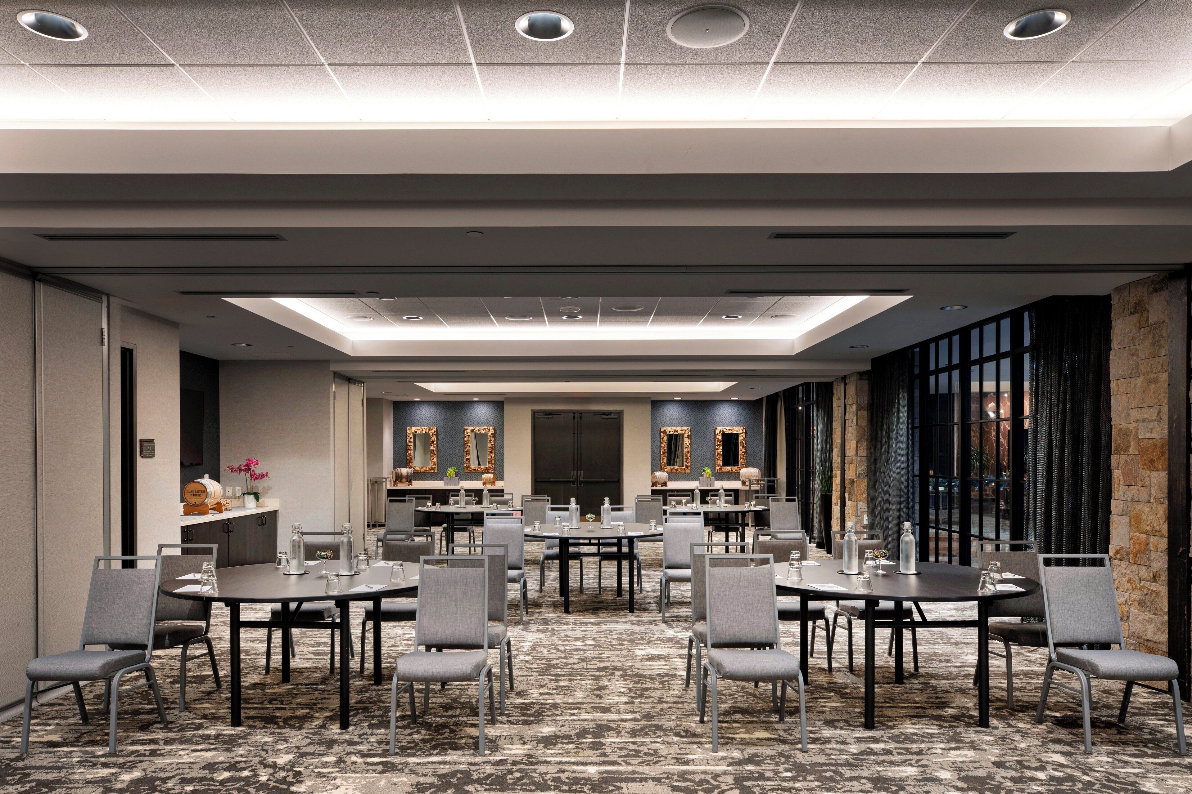 A conference room with multiple tables and chairs, a patterned carpet, and a modern ceiling design.
