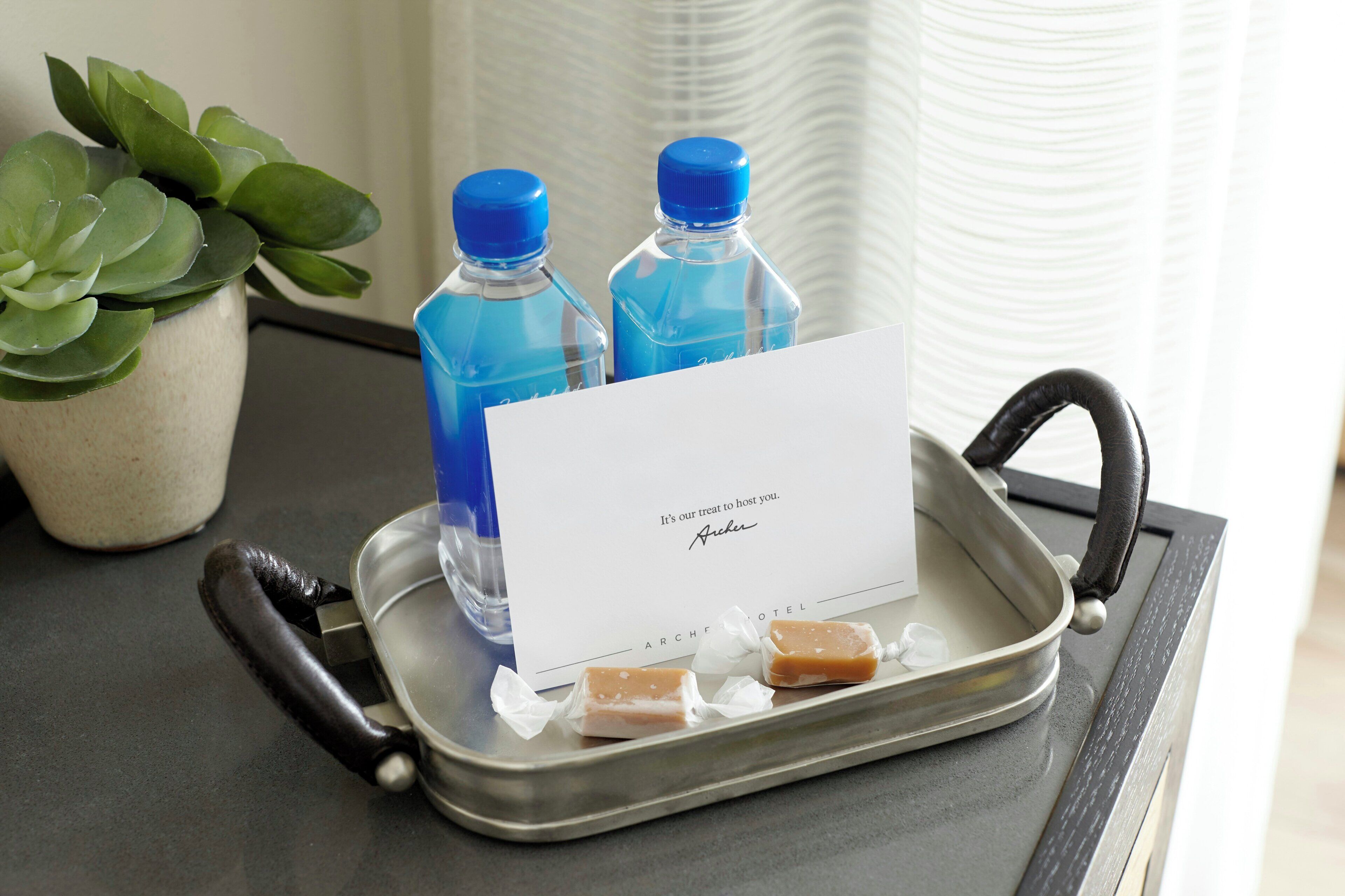 A tray with a card, two water bottles, and two pieces of food on a table.