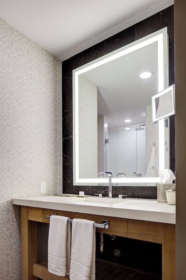 Un baño moderno con un espejo grande, un lavamanos y una zona de ducha.