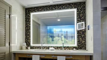A bathroom with a large mirror, two sinks, and a decorative mosaic wall.