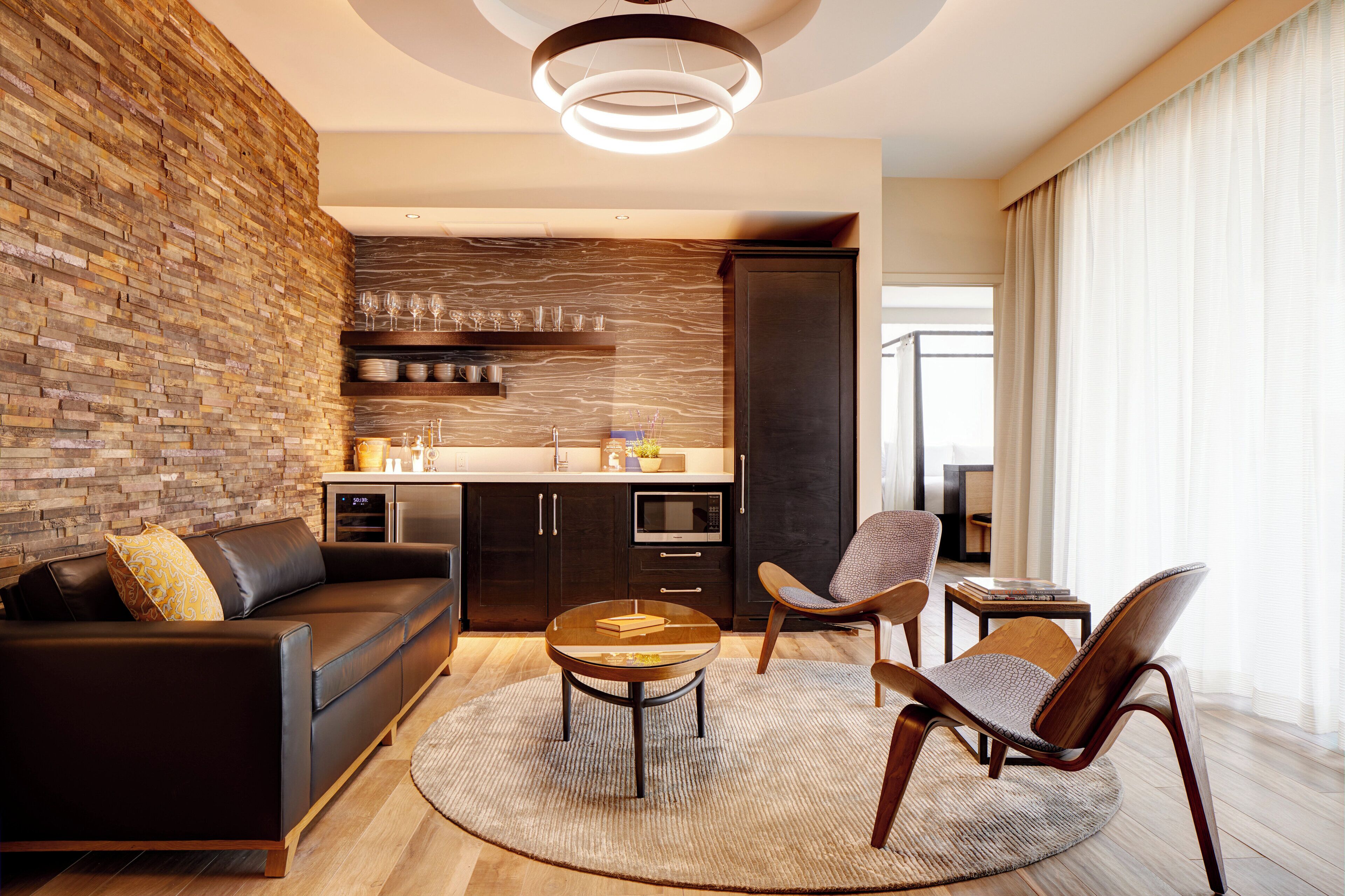 A modern living room with a brick wall, a sofa, a coffee table, and two chairs.