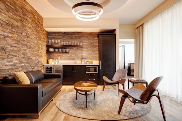 Una sala de estar moderna con una pared de ladrillo, un sofá, una mesa de centro y dos sillones.