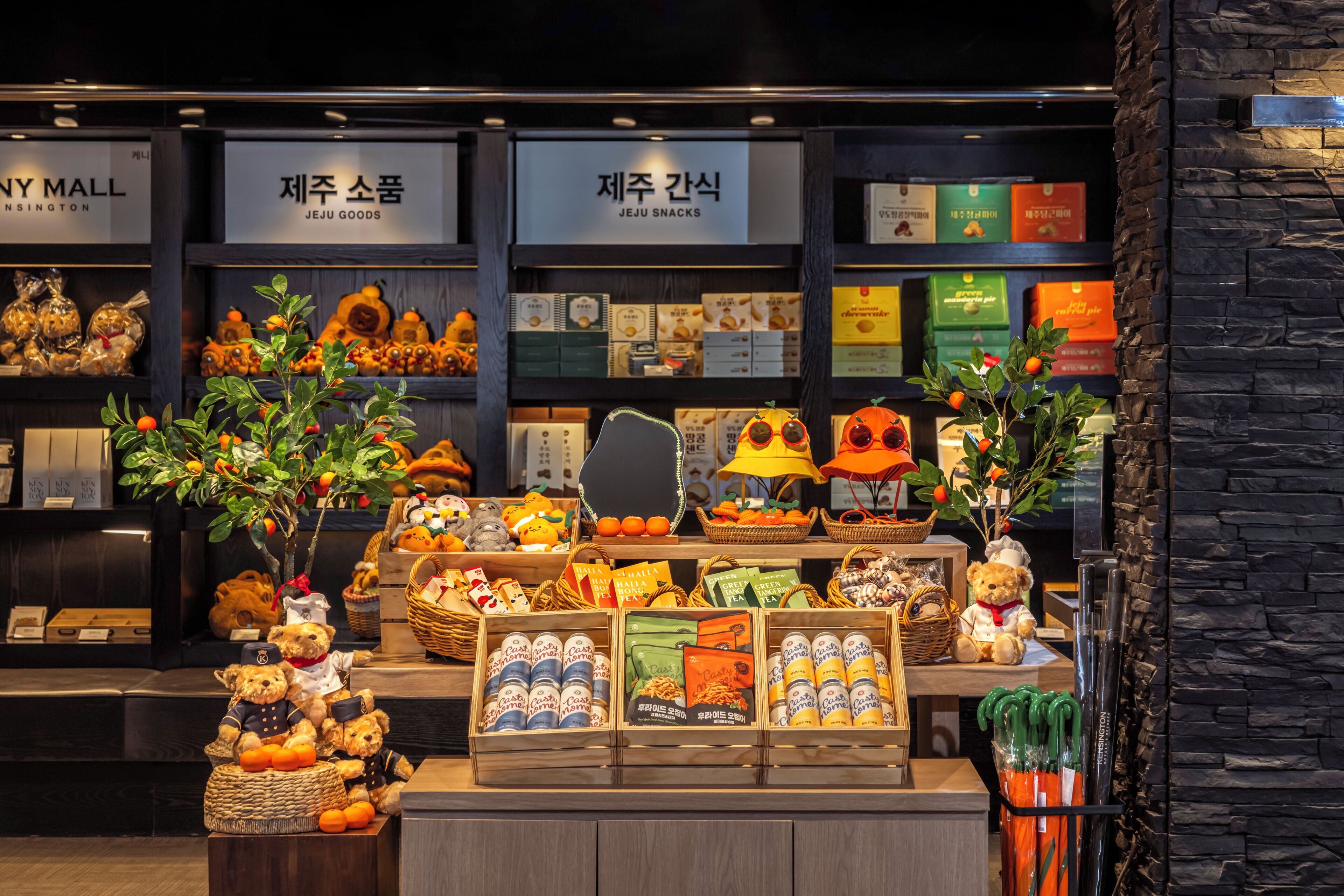 A display of various snacks and goods in a store with signs indicating 'JEJU GOODS' and 'JEJU SNACKS'.